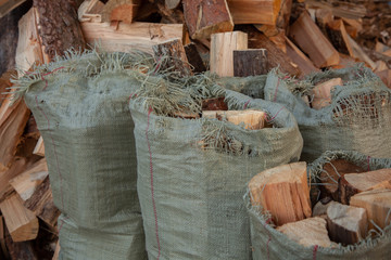 Trees in the sawmill are stacked in bags for sell. Stacks of firewood. Preparation of firewood for the winter. A heap of woodpile. Chopped wood. Firewood.Pile of wood logs ready for winter
