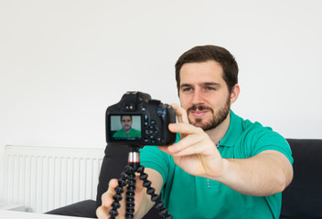 Photo of a young and attractive man with beard getting ready to film a video with a video camera at home