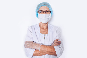 Elderly mature woman doctor or nurse crossed arms in a white medical coat, gloves, face mask wearing personal protective equipment isolated on white background. Healthcare and medicine concept. 