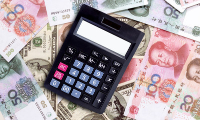 The calculator is placed on a pile of yuan and dollars   banknote.