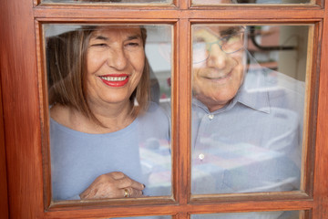 coppia di anziani guarda felice attraverso il vetro di una finestra 