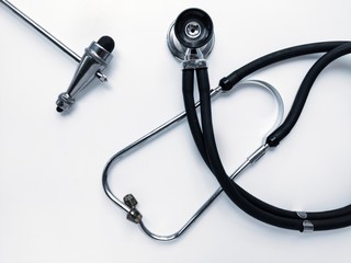 A stethoscope, a neurologist's hammer, a pen on a white desktop.