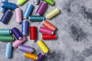 Colorful threads on bobbins, sewing set.On gray concrete background. Place for text.