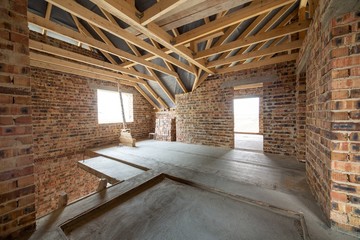 Interior of unfinished brick house with concrete floor, bare walls ready for plastering and wooden...