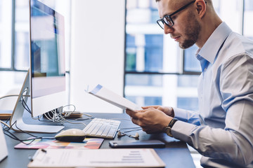 Obraz premium Formal executive reading documents against computer in office