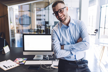 Pleased businessman standing near table in office