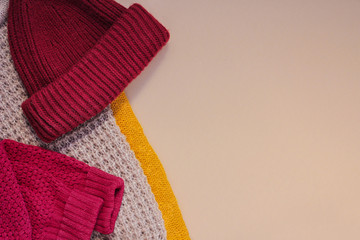 Winter, autumn clothes, knitted scarves, warm sweaters, hat on a brown background. warm cozy comfortable clothes