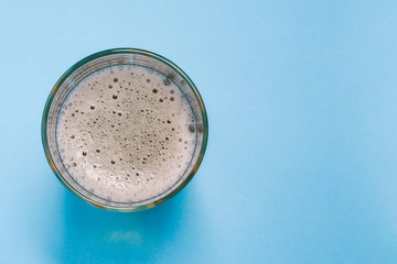 Glass glass with beer or sparkling water on a blue background with a copy of the space. Alcoholic or non-alcoholic refreshing drink. A top view of a flat layout.