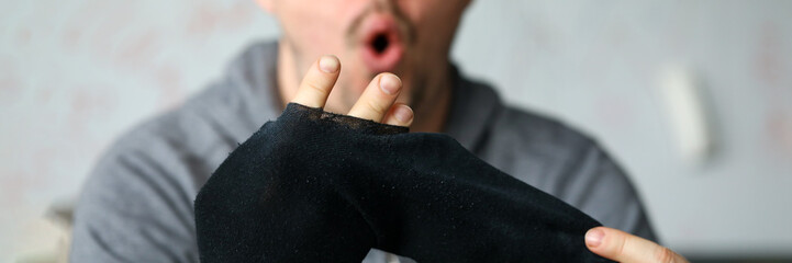 Man sitting at home surprised by big hole socks