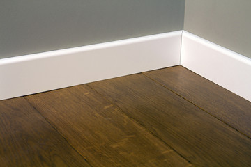 Close up of white plastic plinths on dark wooden oak floor parquet.