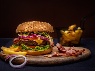 Beef burger and french fries on wooden table isolated on black background