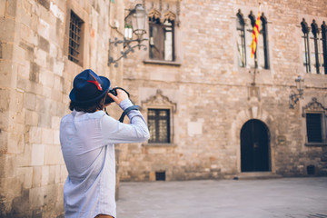 Fototapeta na wymiar Traveler taking photo of medieval building with digital camera in old town