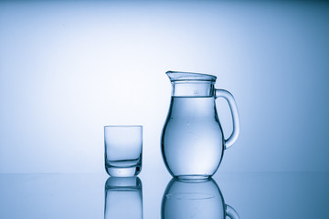 Pitcher with drinking water and a glass with a drink, blue tone