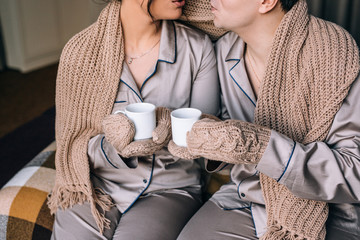 a man and a woman are covered with a warm knitted blanket