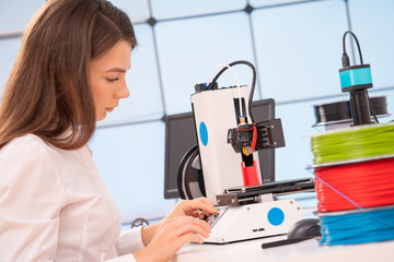 Young female designer working on a prototype device on a 3D printer