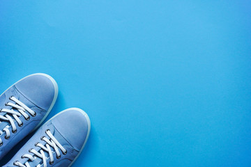 Light blue sneakers with white laces and a white sole on a blue flat lay background. Copy space. Lifestyle, outdoor shoes for walking. Casual unisex