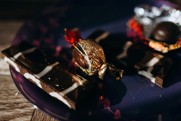 chocolate bright candy on a plate beautiful dish with a red pattern dark background and rays of light