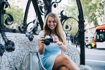 Cheerful Caucasian tourist with sincere smile using vintage technology for editing images resting...