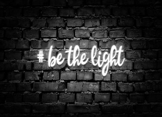 Fototapeta na wymiar Be the light. Shining hashtag on gray brick wall background. Positive message