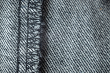 Overlock seam on gray denim pants. Details textile, fabric, selective focus, copy space