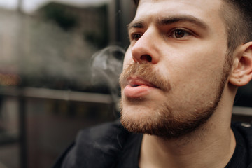 man smokes a cigarette. The spread of cigarette smoke. mustache