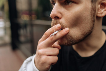 man smokes a cigarette. The spread of cigarette smoke. mustache