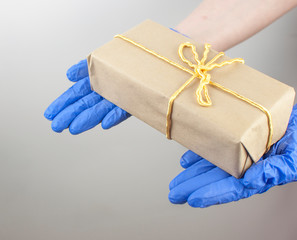 Close up hands delivery man medical gloves hold wrapped cardboard box on white wall background. Service coronavirus. Online shopping. mock up