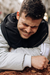 Portrait of a young man walking around the city. Brunette, beard. Cheerful, beautiful smile.