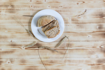 bread slices in white plate on a wooden table and grain spicas