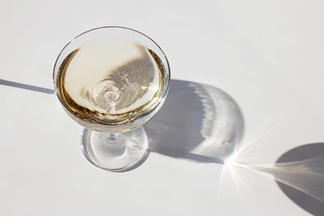 Sparkling wine in a glass on the white table in natural sunlight