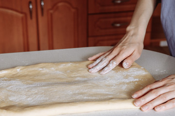 Women's hands and dough. Rolling out the dough.