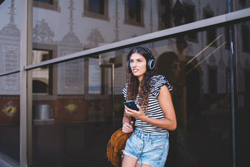 Young woman with headphones and mobile phone resting on street