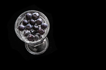 Blueberries in a glass. Black background, space for text