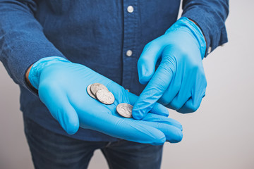Male hand in gloves counting coins close-up.