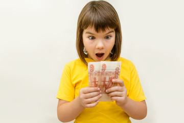 a girl of 8 years of Asian appearance holds in her hands banknotes of 5 thousand Russian rubles on an isolated background finance theme