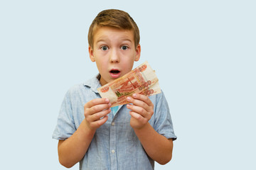 a schoolboy a boy of 10 years of Asian appearance holding in his hands banknotes of 5 thousand Russian rubles on an isolated background finance theme