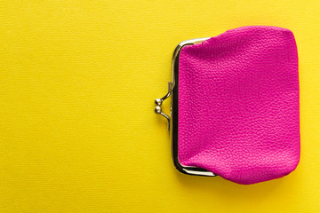 Fashionable pink wallet on a yellow background. Close up.