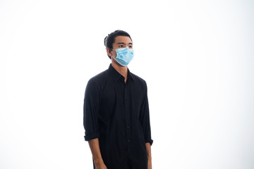 An Asian young man isolated on white background with casual entire and wearing a face mask. Hand gesture stop, sick, respect. during corona virus 