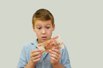 a schoolboy a boy of 10 years of Asian appearance holding in his hands banknotes of 5 thousand Russian rubles on an isolated background finance theme