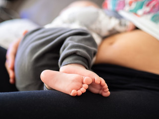 detail of the baby feet sleeping over his mother with blurred background