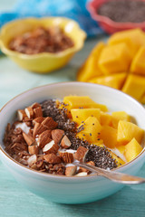 mango and greek yoghurt with seeds and nuts on wooden surface