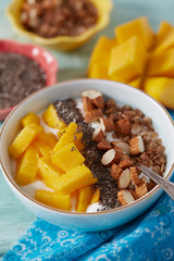 mango and greek yoghurt with seeds and nuts on wooden surface
