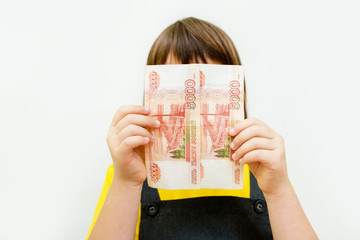 a girl of 8 years of Asian appearance holds in her hands banknotes of 5 thousand Russian rubles on an isolated background finance theme