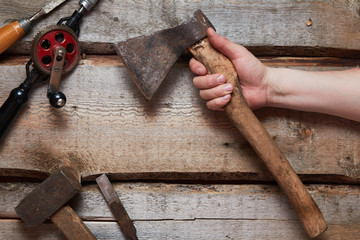 Hand holds old carpentry tools on wooden background.