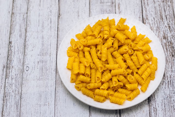 Dry pasta in the form of a spiral on a white plate.