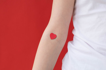 The concept of blood donation, the hand of a girl with a red heart on a bend