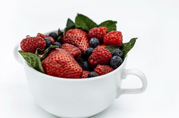 Summer berries in a cup strawberries, mint, raspberries, blueberries on a white background