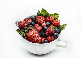 Summer berries in a cup strawberries, mint, raspberries, blueberries on a white background