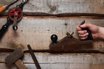 Hand holds old carpentry tools on wooden background.