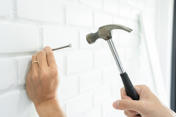 Handyman hammering a nail for House with siding panels, construction work and renovation service.